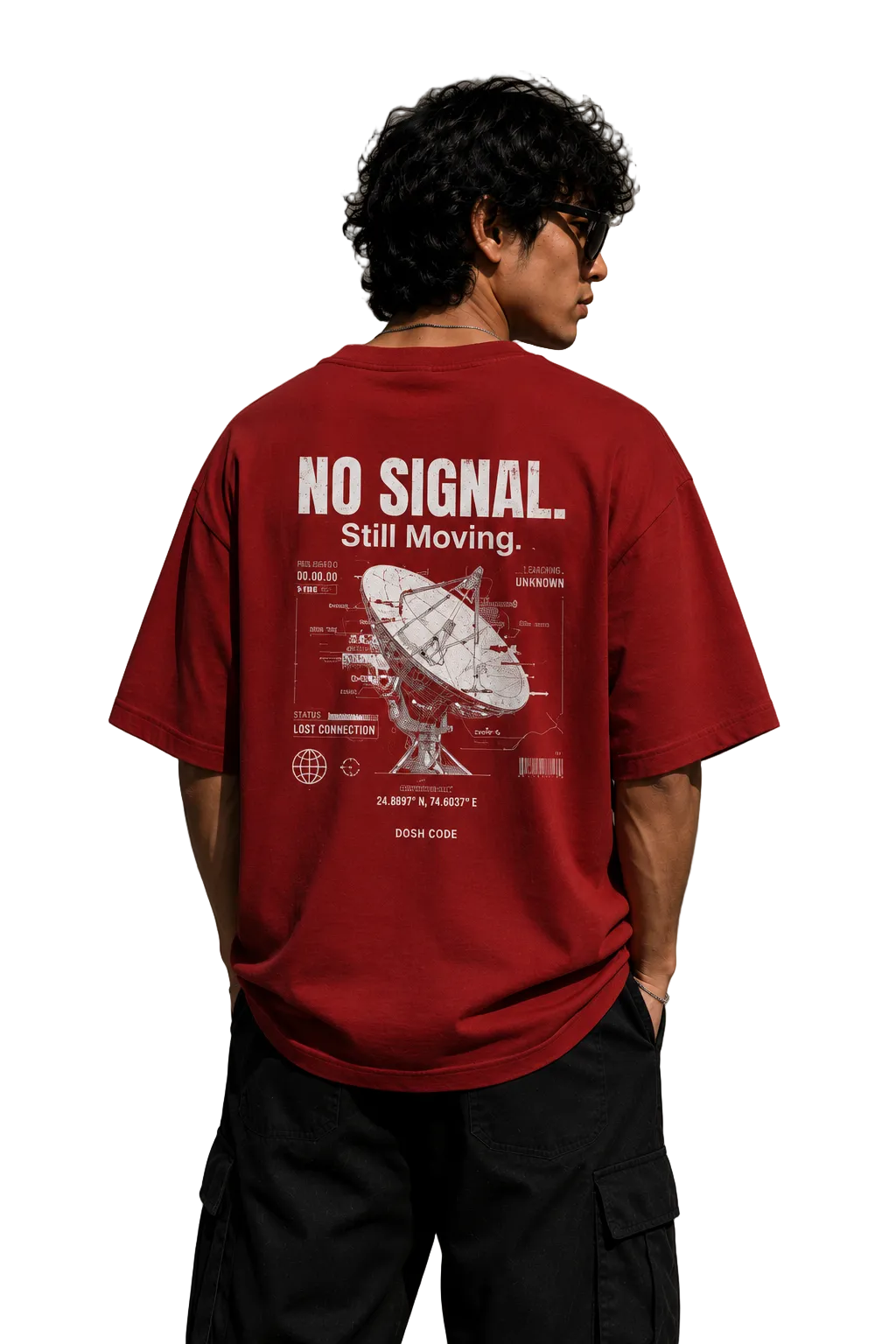A man wearing a red graphic t-shirt with white text and a satellite dish design on the back, standing against a concrete wall.